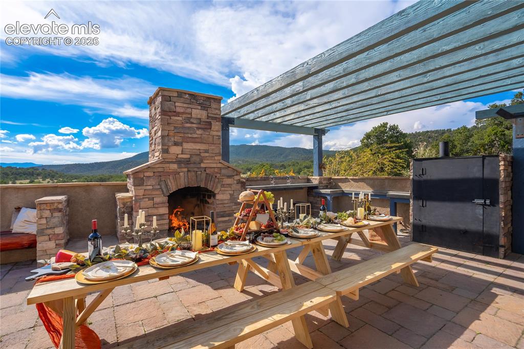 Image 14 of 50: Expansive outdoor patio featuring a stone-clad fireplace, a built-in outdoo