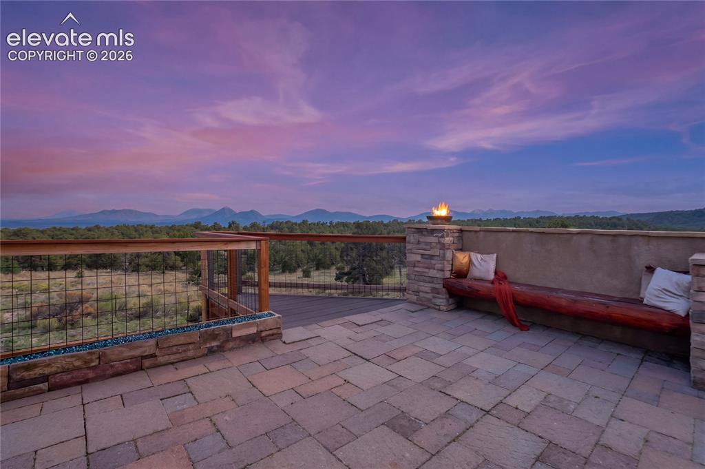 Image 15 of 50: Paver patio with a stone-clad half-wall, built-in wooden bench, and a moder