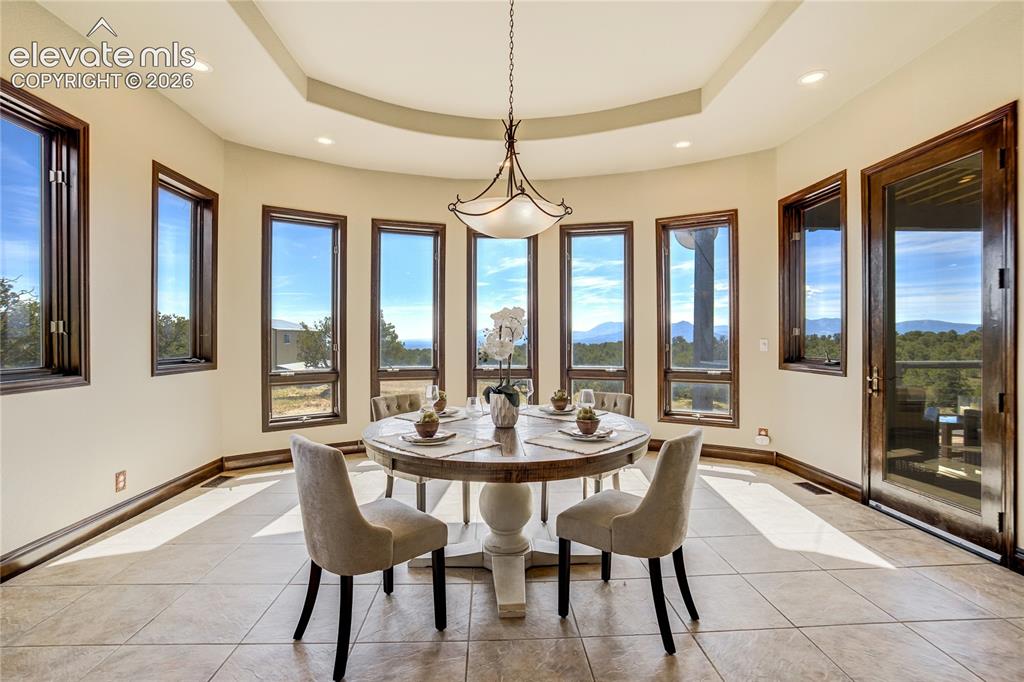 Image 19 of 50: Curved room with multiple windows, a tray ceiling, recessed lighting, a gla