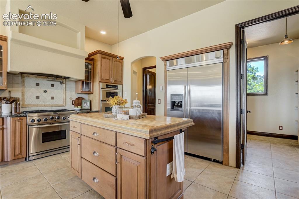 Image 21 of 50: Kitchen featuring a substantial wood island with stone countertop, stainles