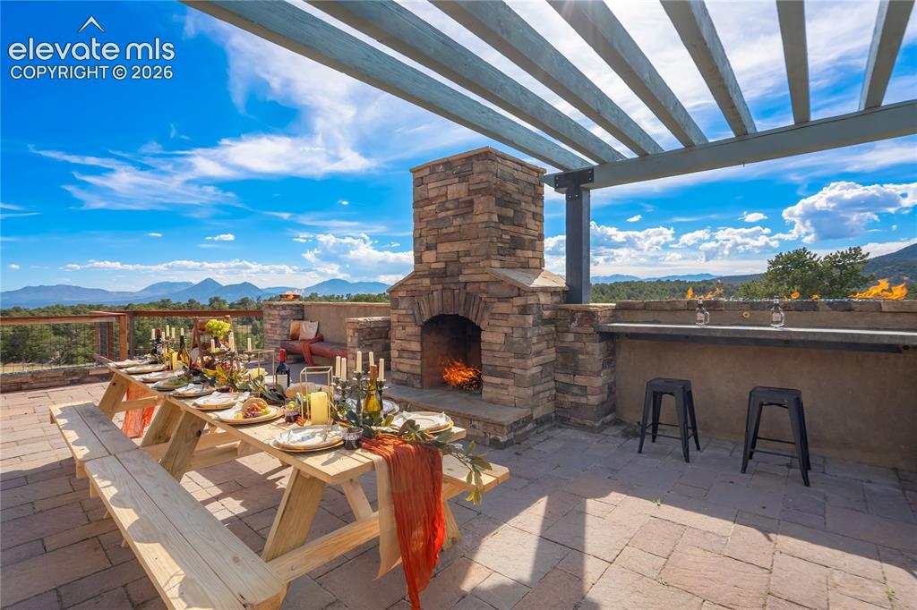 Image 3 of 50: Expansive outdoor patio featuring a stone-clad fireplace and an outdoor bar