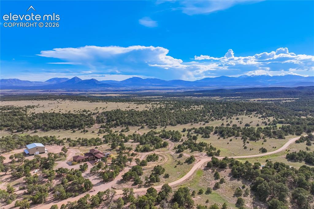 Image 8 of 50: Expansive natural landscape featuring scattered trees, a single-story resid