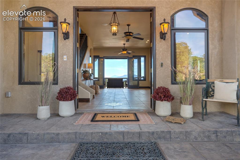 Image 9 of 50: Stucco exterior with arched windows, exterior sconce lighting, and a stone-
