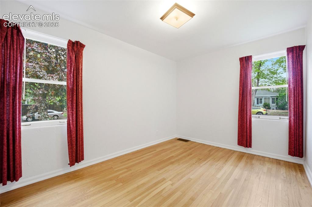 Image 14 of 46: Bright room featuring two large windows, wood-finish flooring, white walls,
