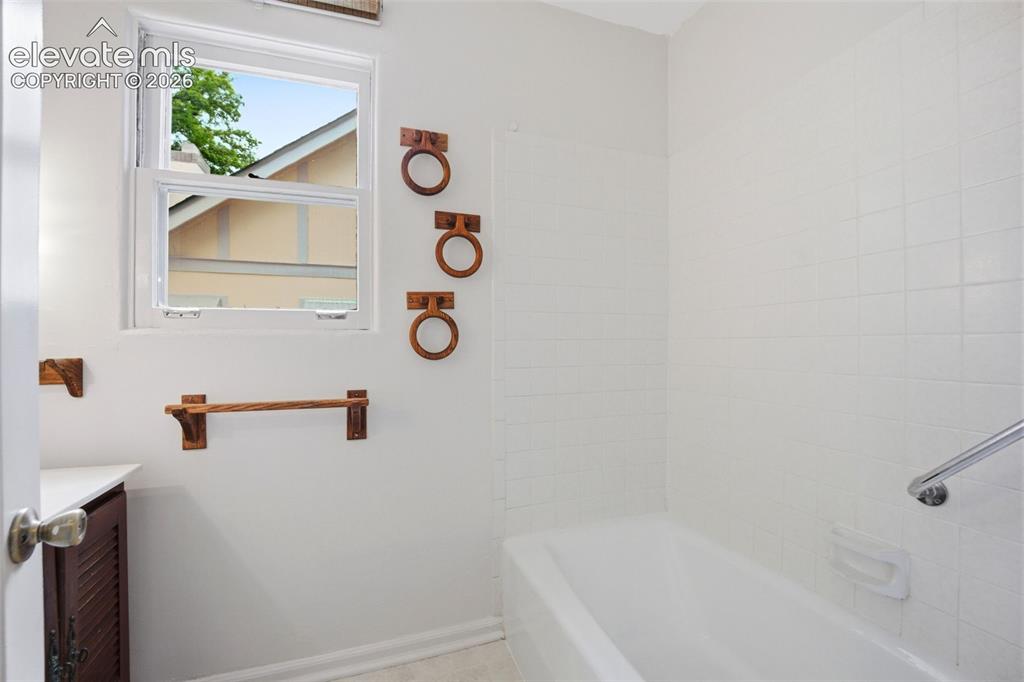 Image 16 of 46: Bathroom featuring a window, white subway tile shower surround, a built-in 