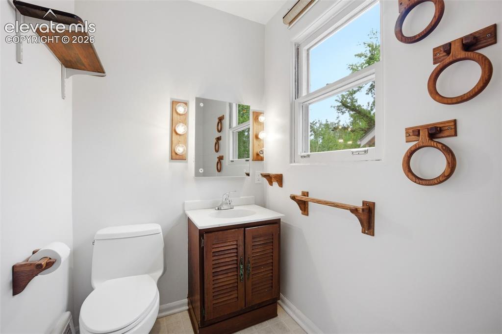 Image 17 of 46: Bathroom featuring a single-pane window, white walls, and wood-finish floor