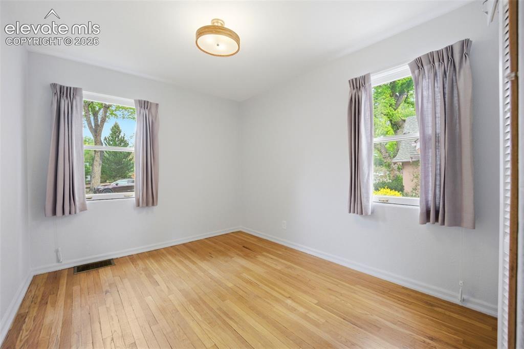 Image 18 of 46: Bright room with wood-finish flooring, two large windows, a ceiling-mounted