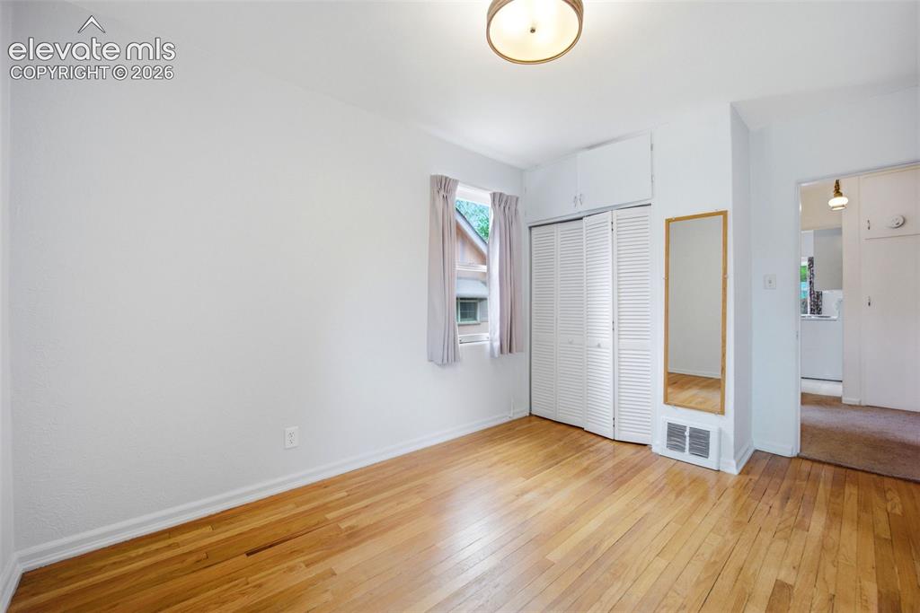 Image 20 of 46: Wood-finish flooring throughout this room with white walls and baseboards