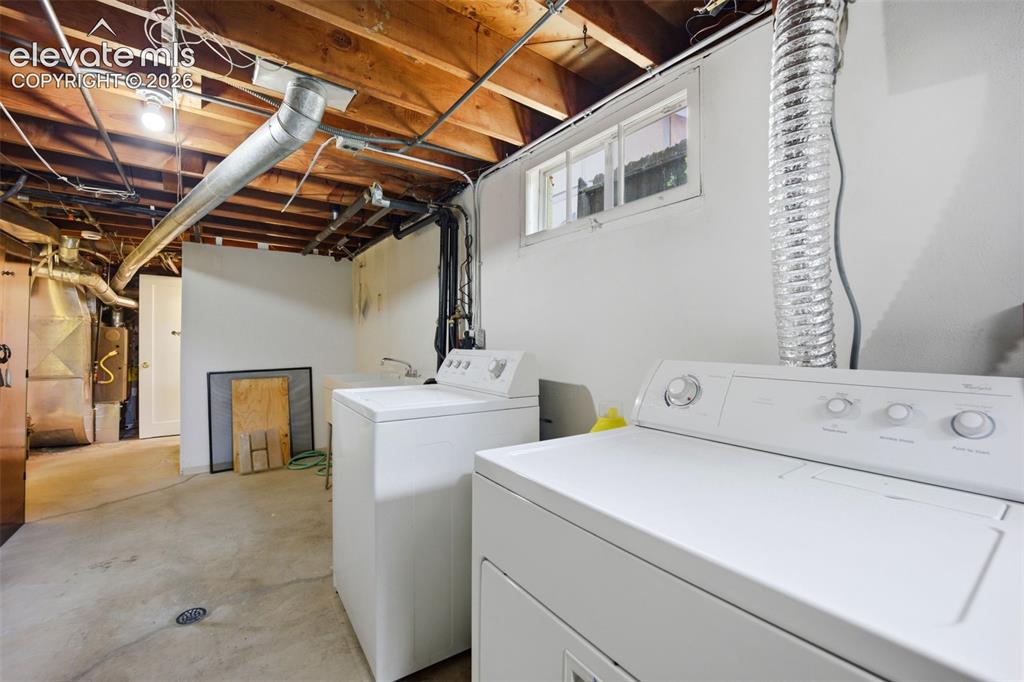 Image 27 of 46: Laundry area featuring exposed wood ceiling joists, concrete flooring, and 