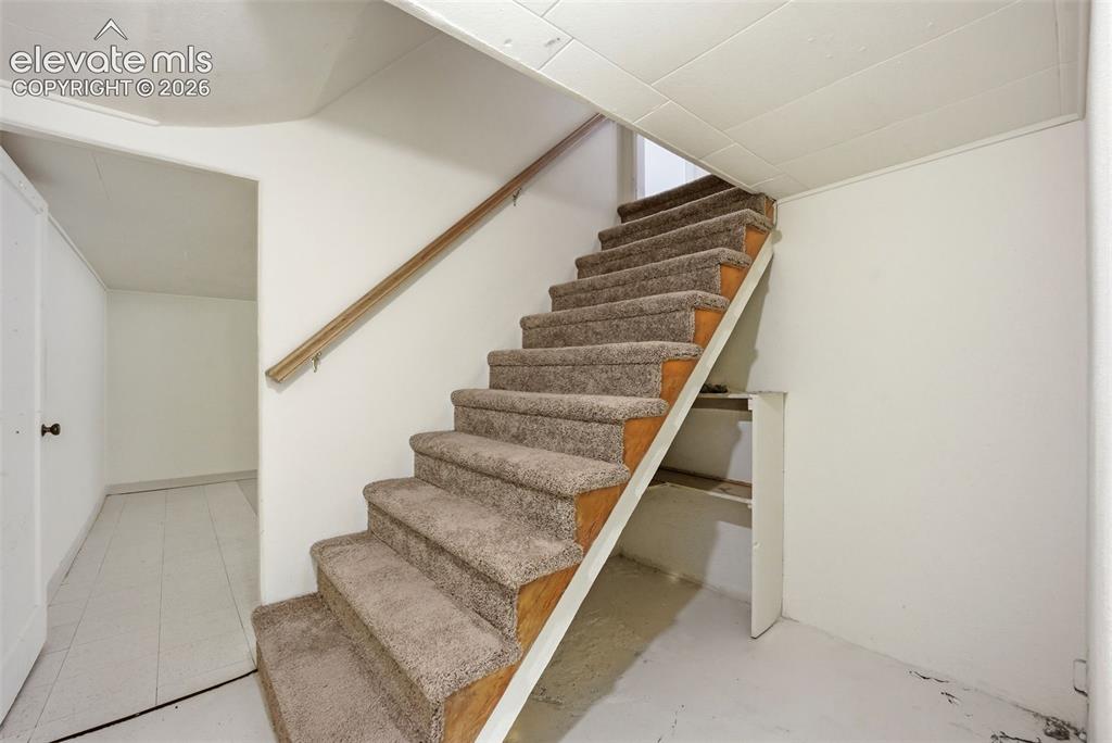Image 29 of 46: Carpeted staircase with a wood handrail and painted walls