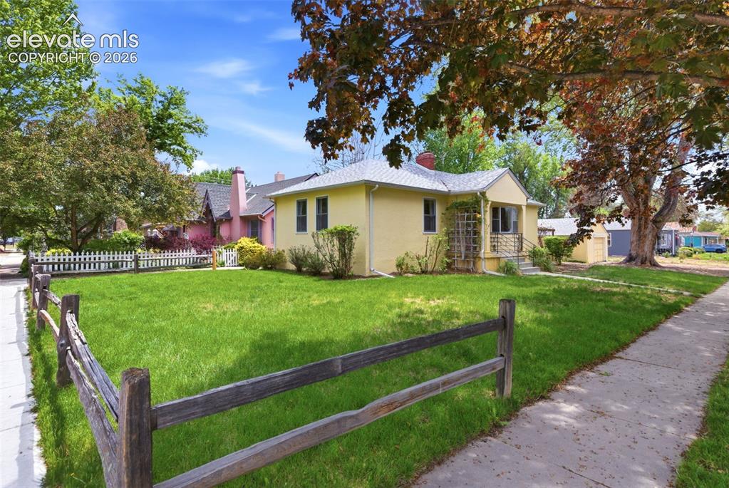 Image 35 of 46: Classic yellow stucco home featuring a pitched roof and a charming front po