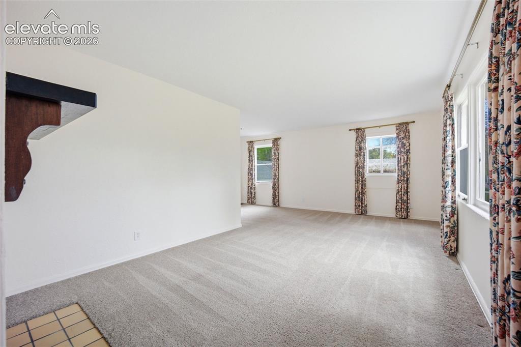 Image 4 of 46: Spacious room featuring light-colored carpeting, multiple windows, white wa