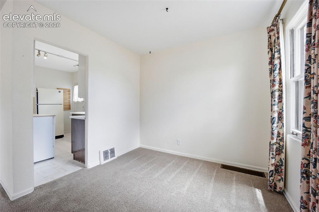 Image 8 of 46: Spacious room with light neutral wall tones and plush carpet flooring