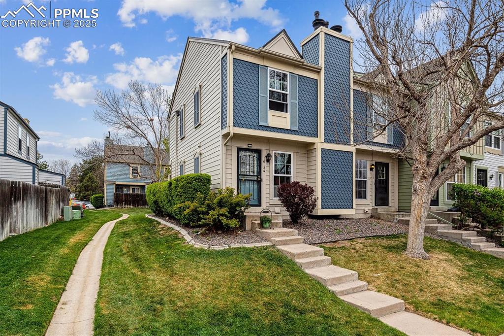 Caption: Multi unit property featuring fence, a chimney, and a front lawn