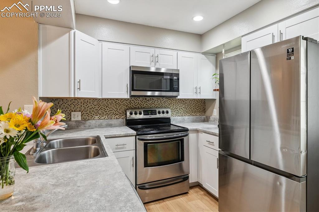 Image 11 of 24: Kitchen featuring light countertops, white cabinets, tasteful backsplash, a