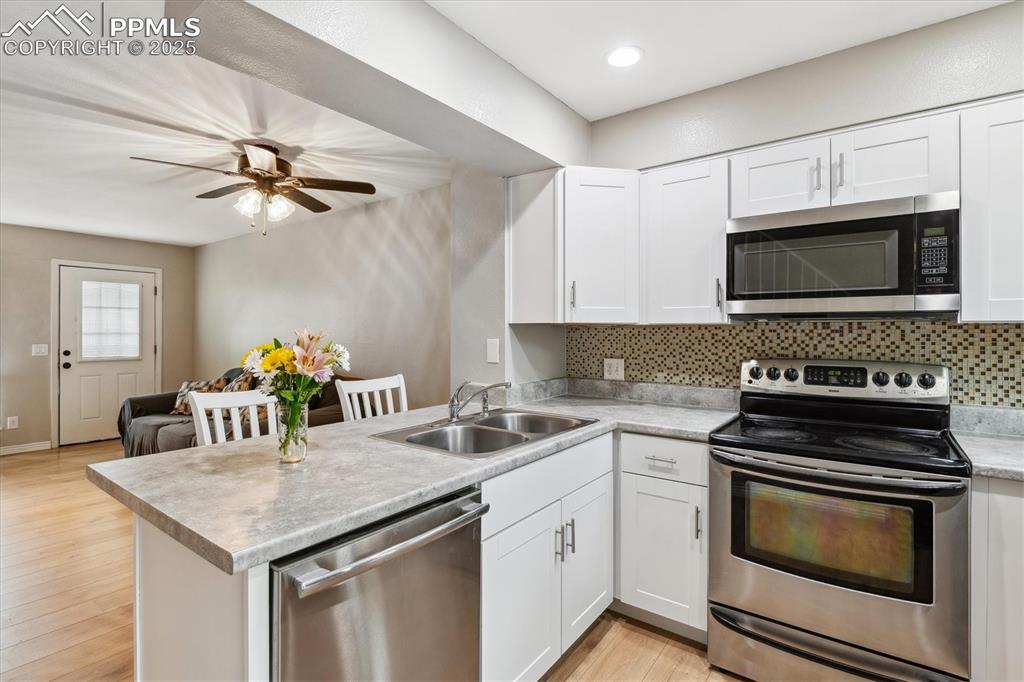 Image 12 of 24: Kitchen with a sink, a peninsula, backsplash, and stainless steel appliance