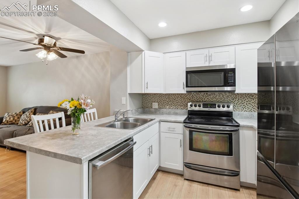Image 13 of 24: Kitchen with a peninsula, open floor plan, light countertops, a sink, and a
