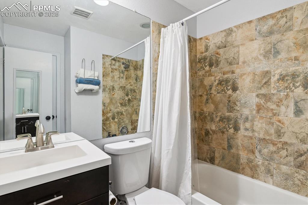 Image 18 of 24: Bathroom with vanity, toilet, visible vents, and shower / bath combo with s