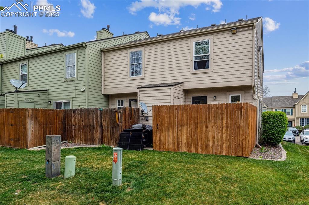 Image 24 of 24: Rear view of property with a lawn, fence, and a chimney