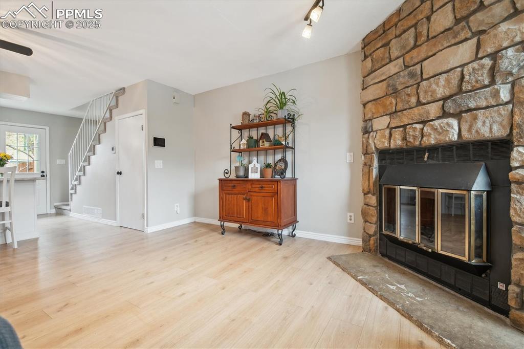 Image 5 of 24: Living room with baseboards, wood finished floors, stairway, and a fireplac