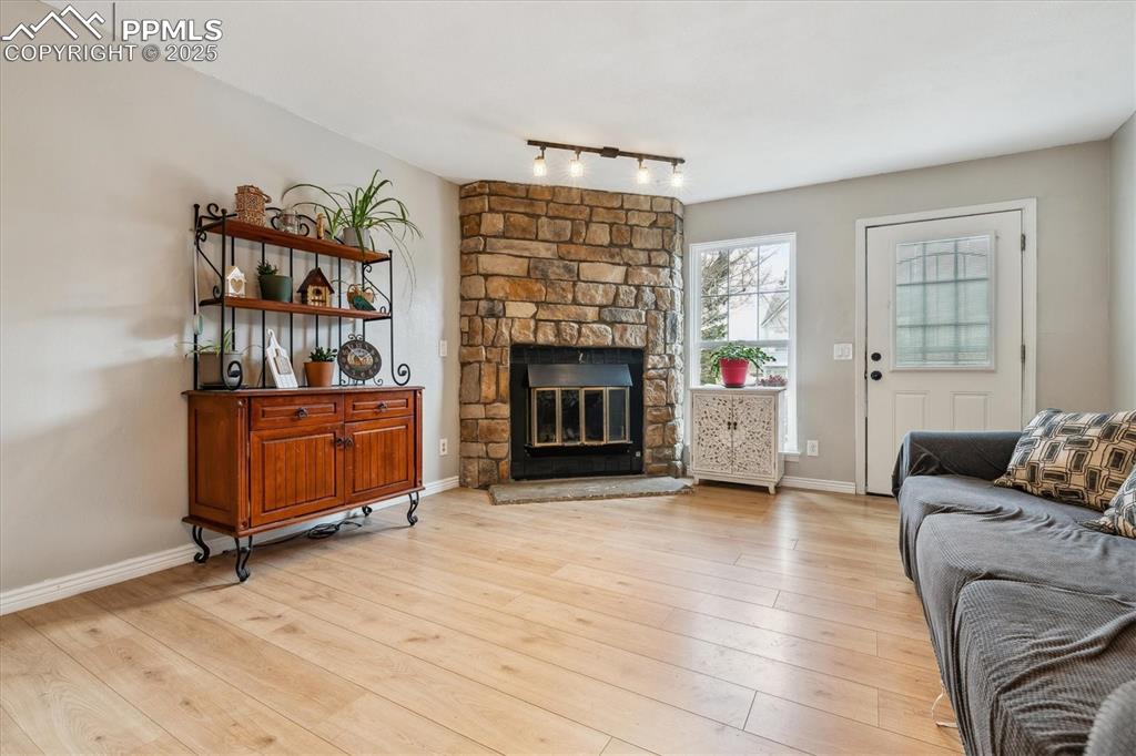 Image 6 of 24: Living area with light wood-type flooring, track lighting, baseboards, and