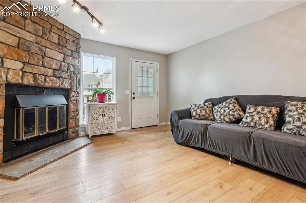 Image 7 of 24: Living area with track lighting, a large fireplace, baseboards, and wood fi