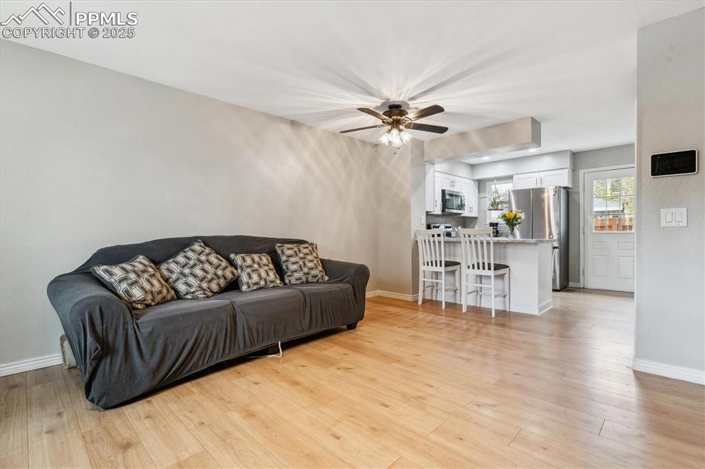 Image 8 of 24: Living room featuring light wood-style floors, baseboards, and ceiling fan