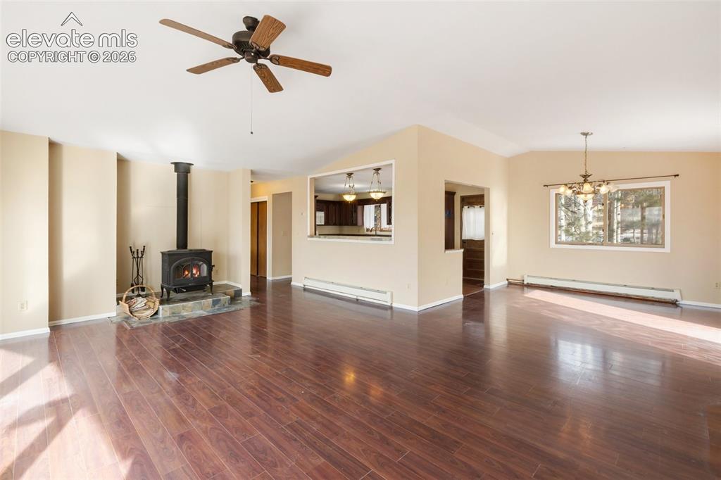 Image 13 of 40: Hardwood-style flooring, a wood-burning stove on a stone hearth, and an ope