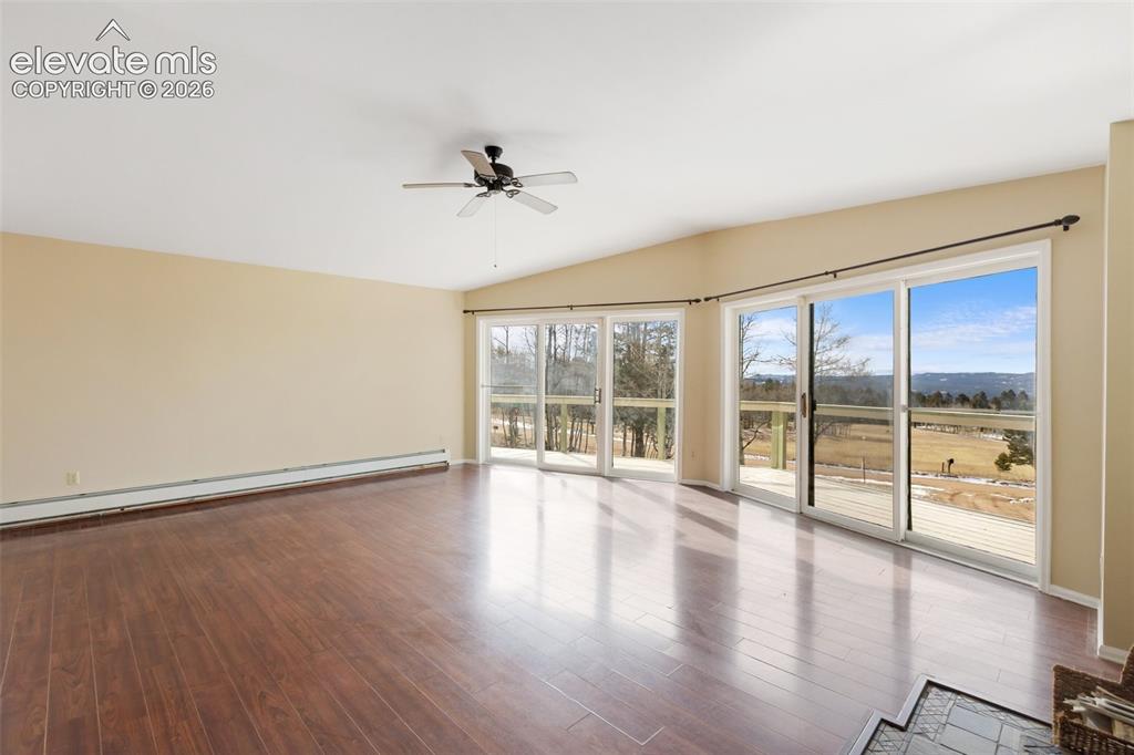 Image 14 of 40: Wood-finish flooring, vaulted ceiling, ceiling fan, multiple sliding glass 