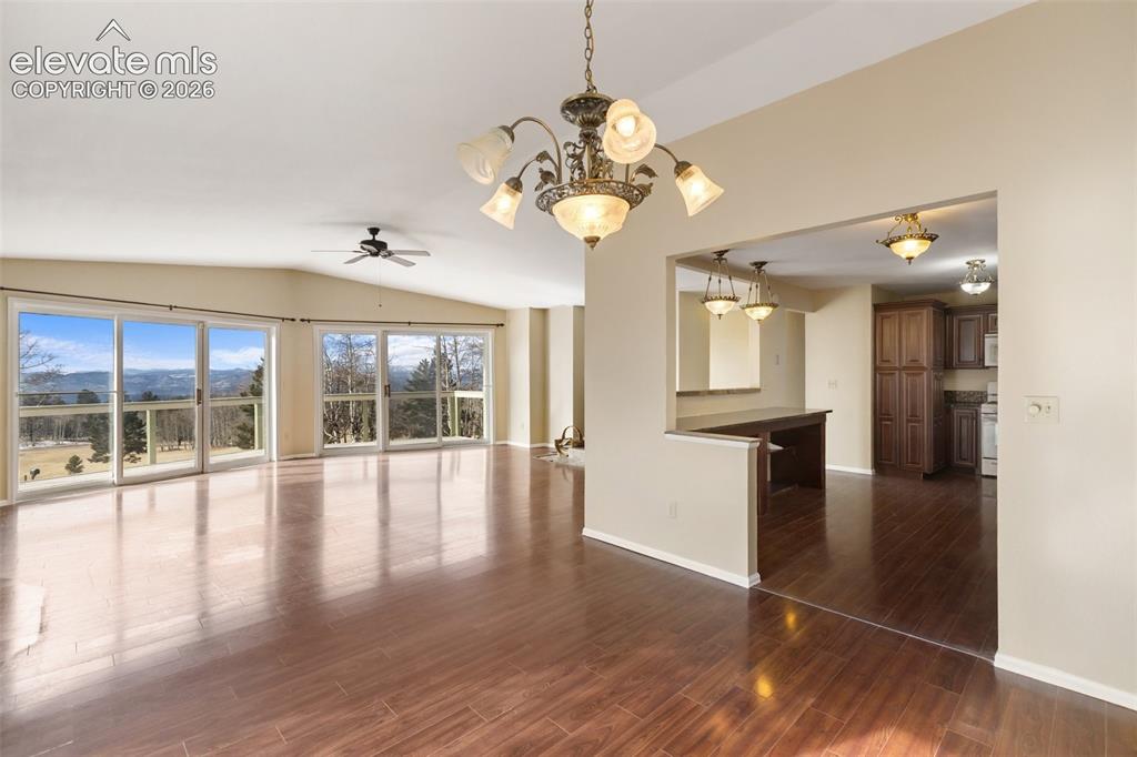Image 16 of 40: Open-concept living area featuring wood-finish flooring, vaulted ceiling, a