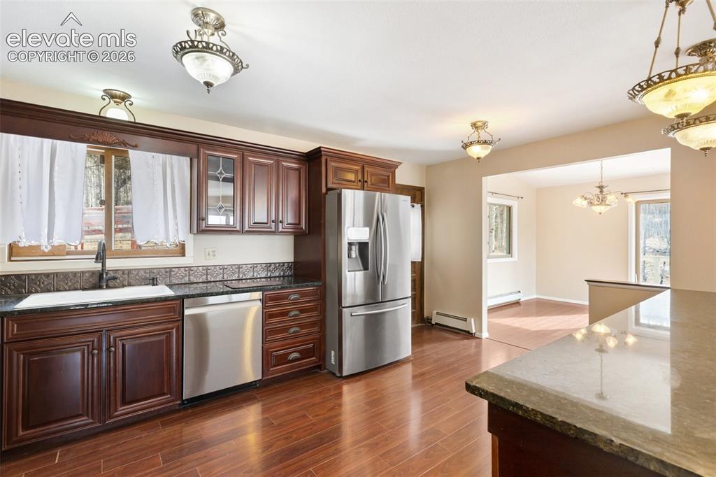 Image 17 of 40: Rich wood-finish flooring, dark wood cabinetry, and stainless steel applian