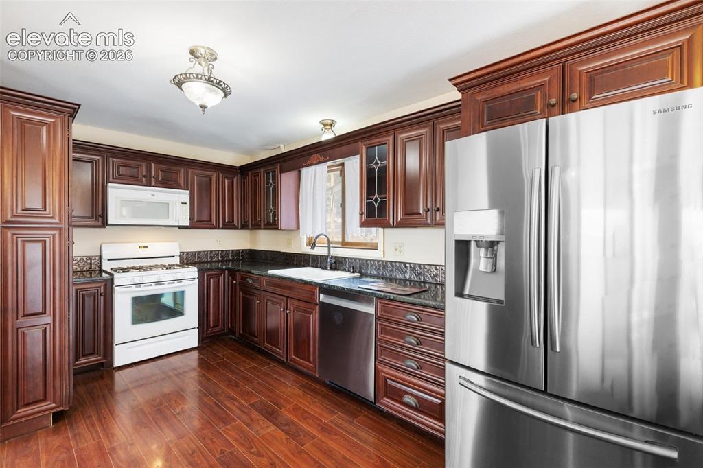 Image 18 of 40: Rich wood cabinetry with crown molding, stainless steel appliances, dark st