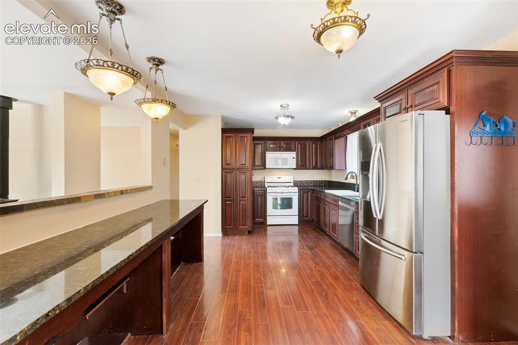 Image 20 of 40: Kitchen featuring dark wood-finish cabinetry, stainless steel refrigerator,