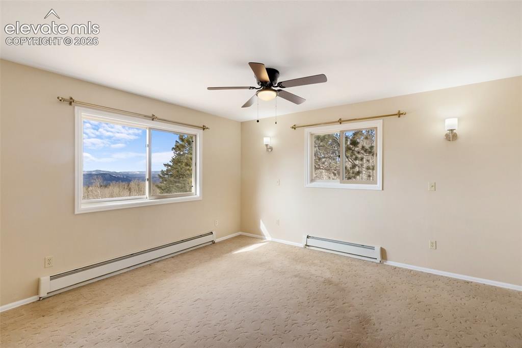 Image 21 of 40: Wall-to-wall carpeted room with multiple windows, a ceiling fan, and wall s