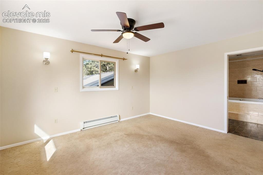 Image 22 of 40: Spacious room featuring a ceiling fan, wall sconces, window, and neutral ca