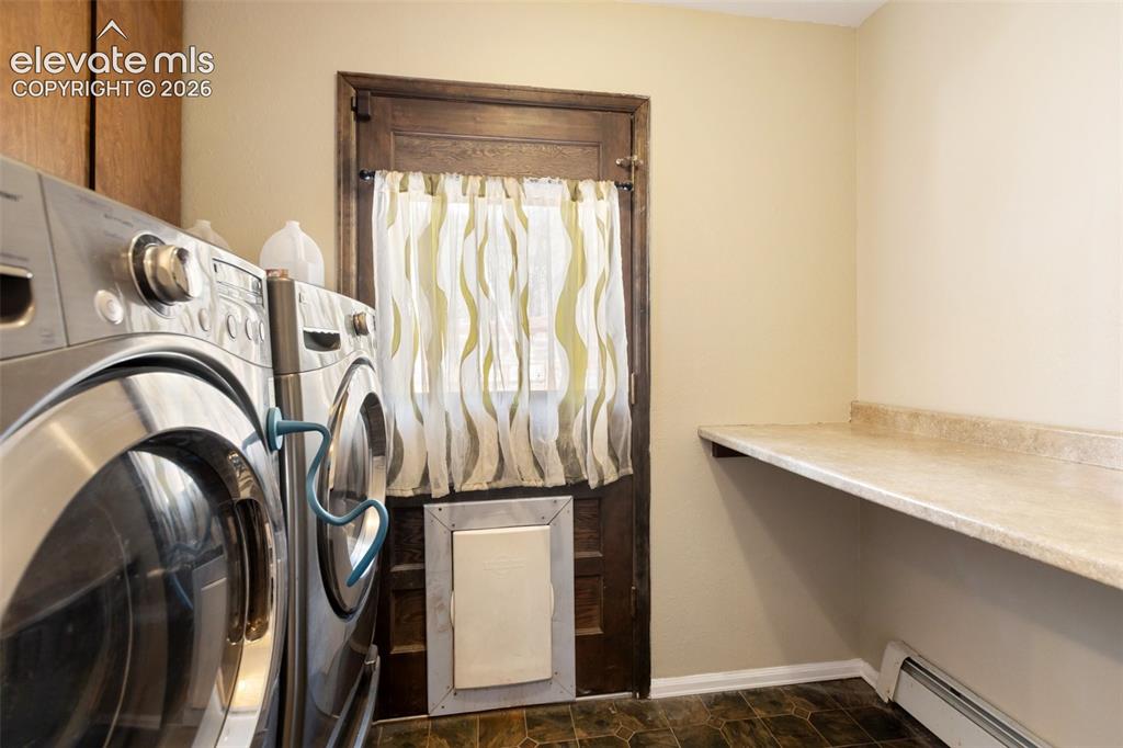 Image 27 of 40: Laundry area featuring a wood-finish door, durable flooring, and built-in c