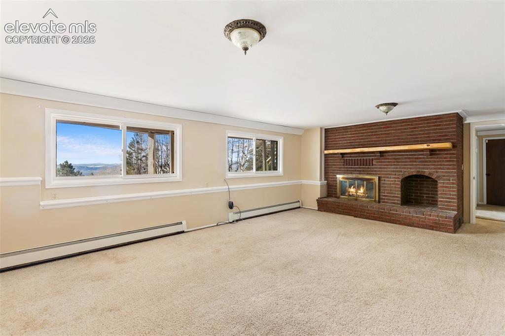 Image 28 of 40: Expansive room featuring a red brick fireplace with a wood mantel, light-co