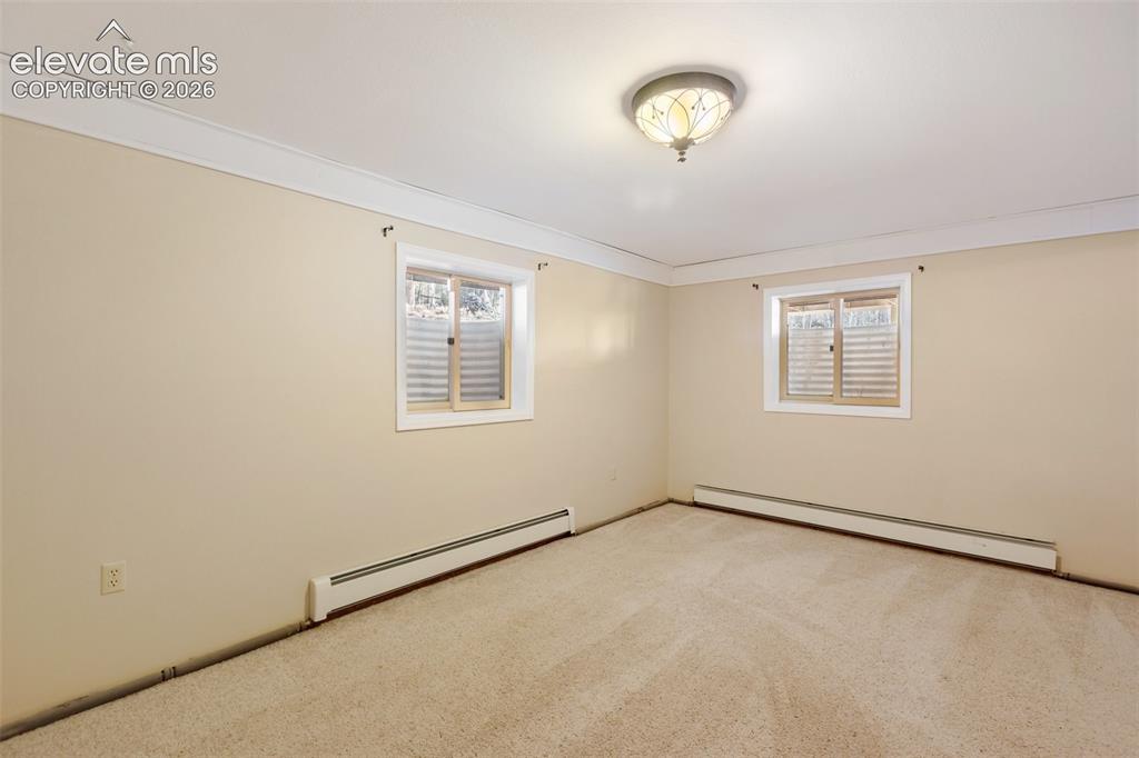 Image 30 of 40: Neutral-toned carpeting, two windows with blinds, a ceiling-mounted light f