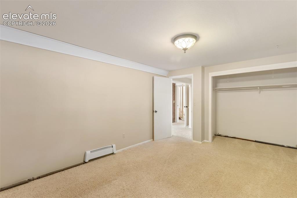 Image 31 of 40: Wall-to-wall carpeting, crown molding, and a built-in closet with shelving 