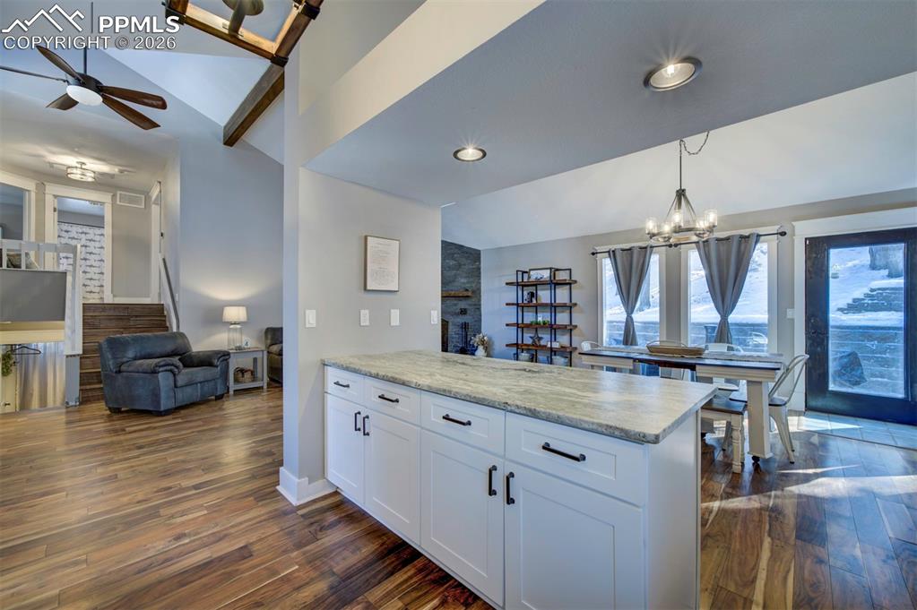 Image 16 of 29: Kitchen featuring vaulted ceiling, a chandelier, white cabinets, open floor