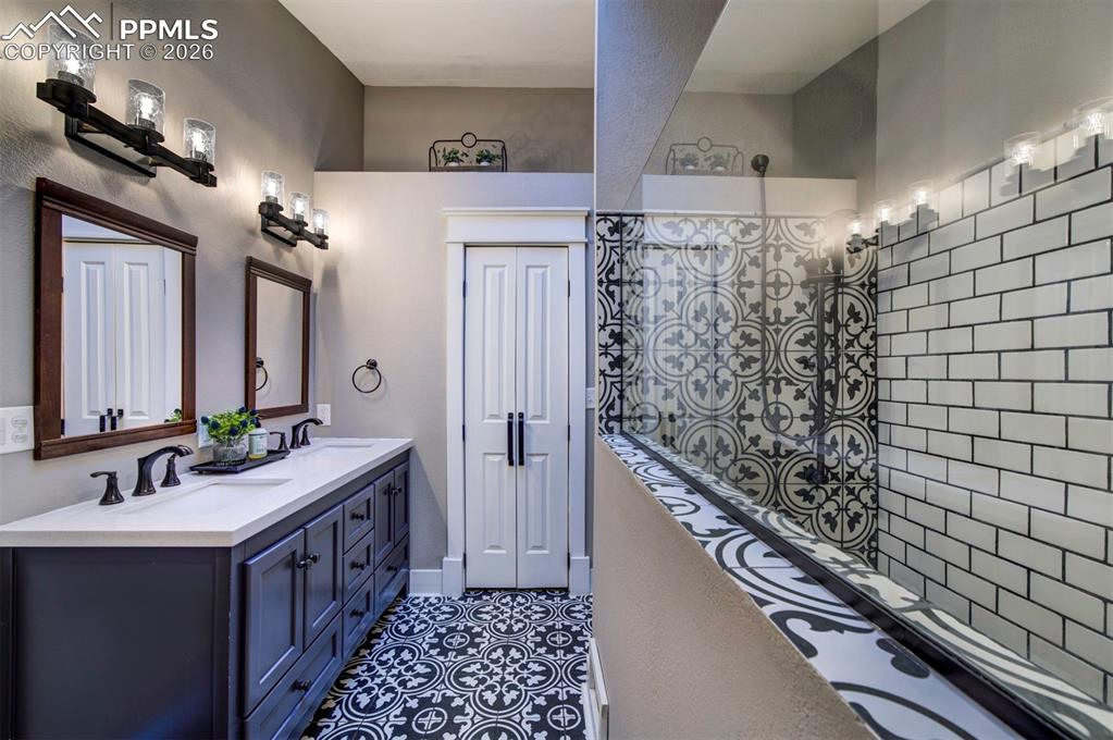 Image 19 of 29: Bathroom featuring double vanity and dark tile patterned floors