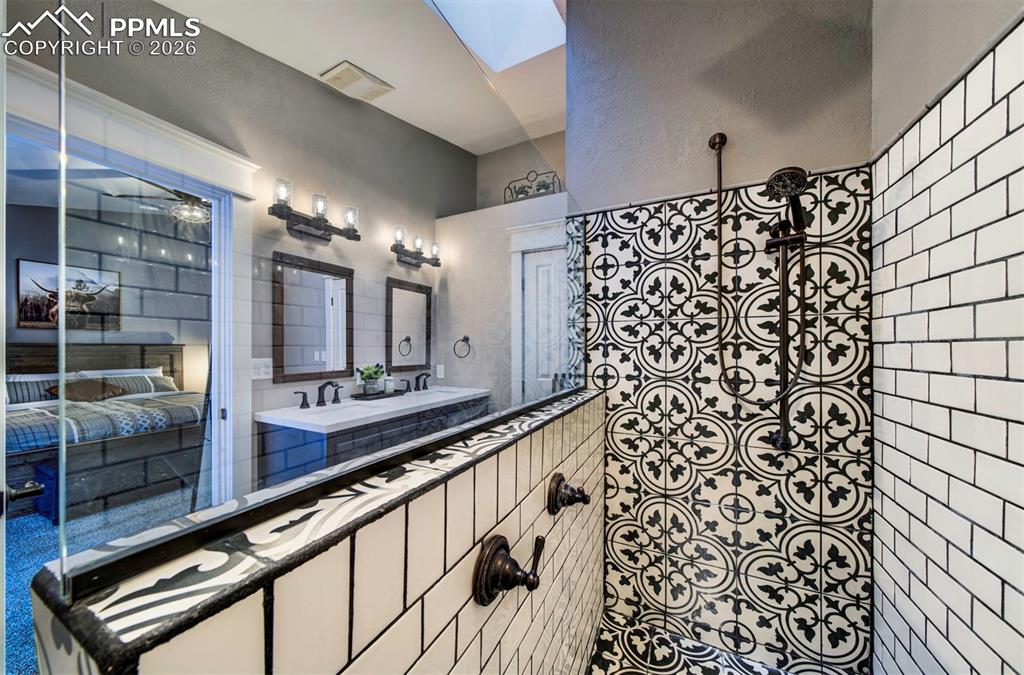 Image 21 of 29: Bathroom featuring double vanity, a skylight, and a ceiling fan