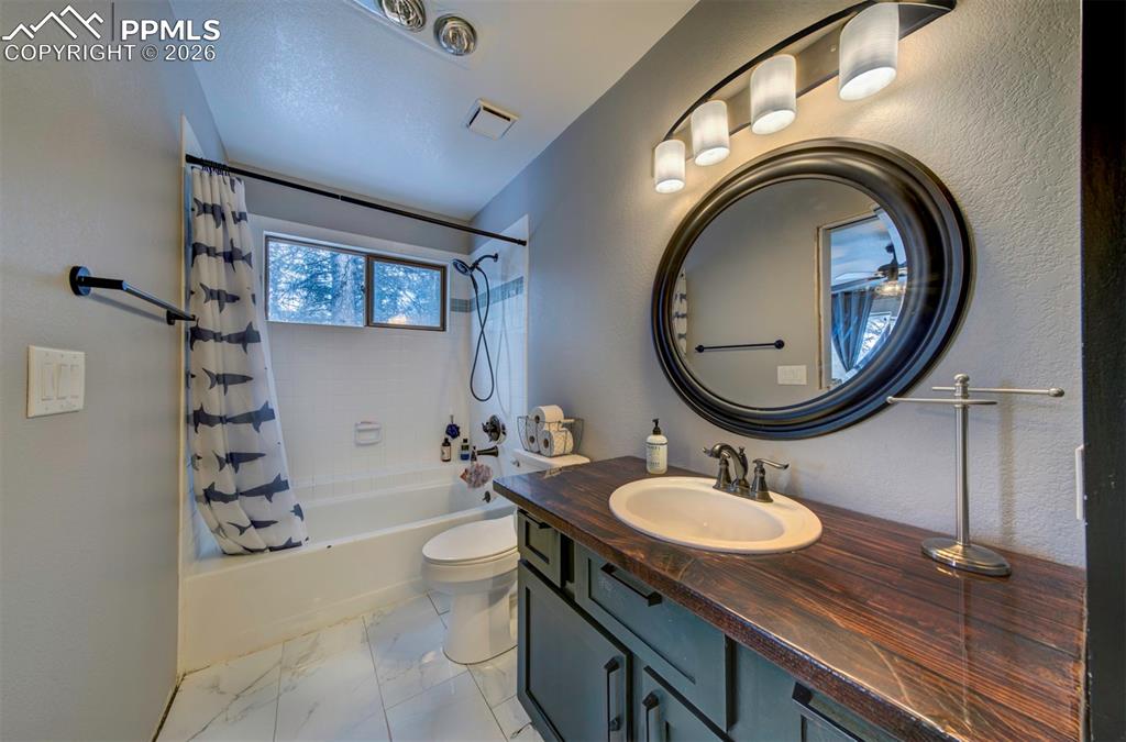 Image 23 of 29: Bathroom with shower / tub combo, vanity, and light marble finish floors