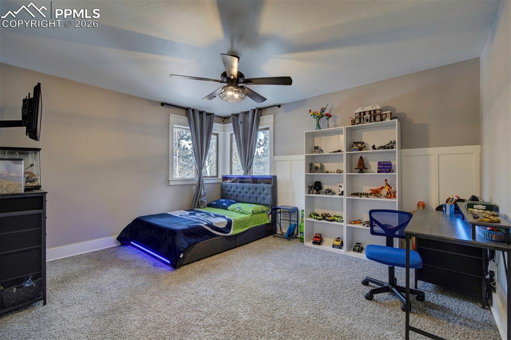 Image 24 of 29: Bedroom featuring carpet, a ceiling fan, and a wainscoted wall