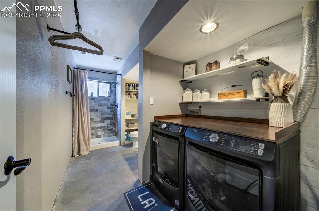 Image 25 of 29: Bar area featuring open shelves, concrete floors, washer and dryer, and but