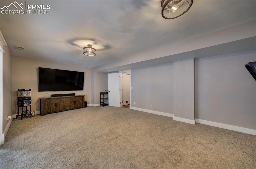 Image 27 of 29: Unfurnished living room with baseboards and light colored carpet