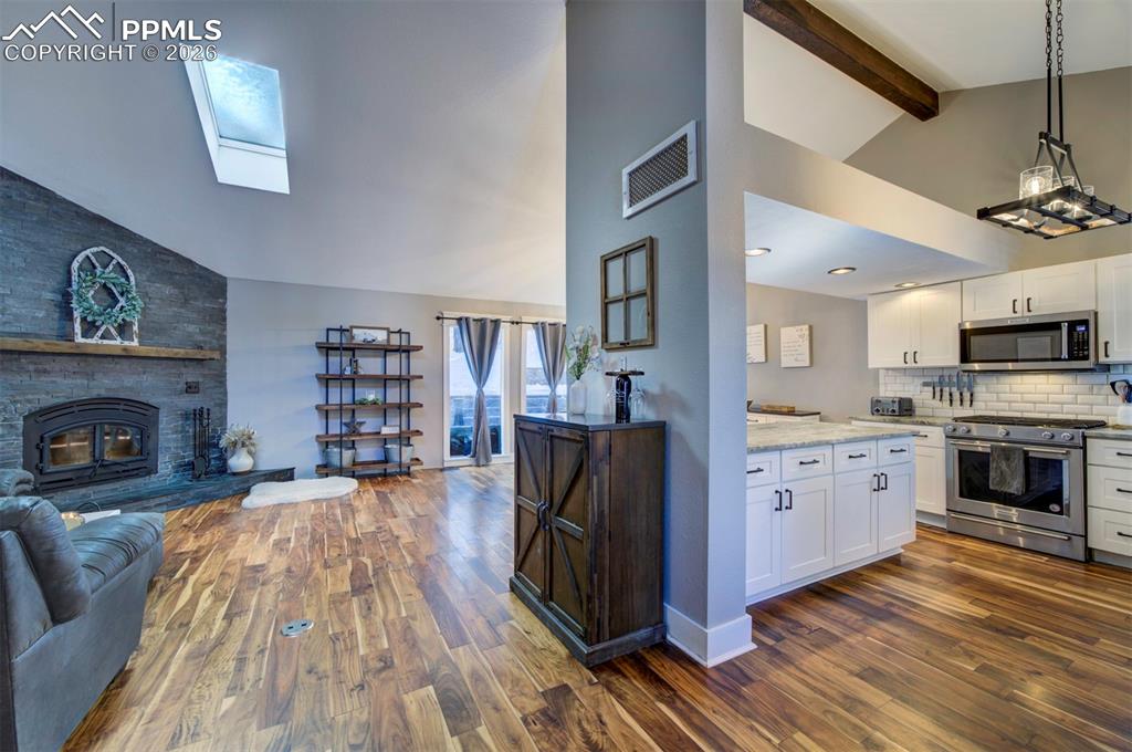 Image 7 of 29: Kitchen featuring a skylight, stainless steel appliances, high vaulted ceil