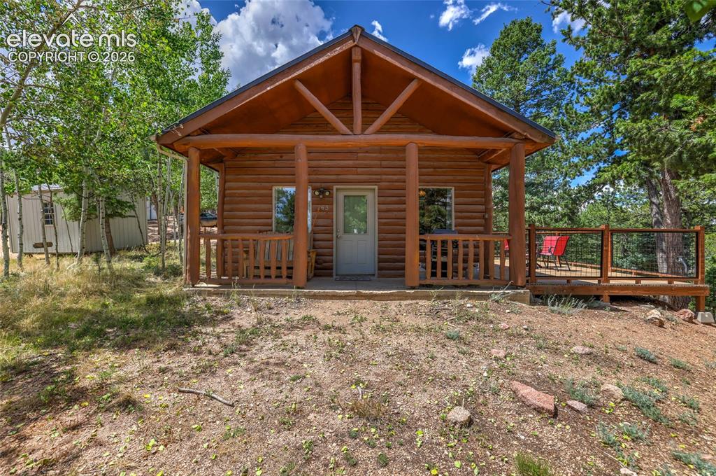 Image 1 of 28: Log cabin exterior featuring a covered front porch, exposed timber framing,