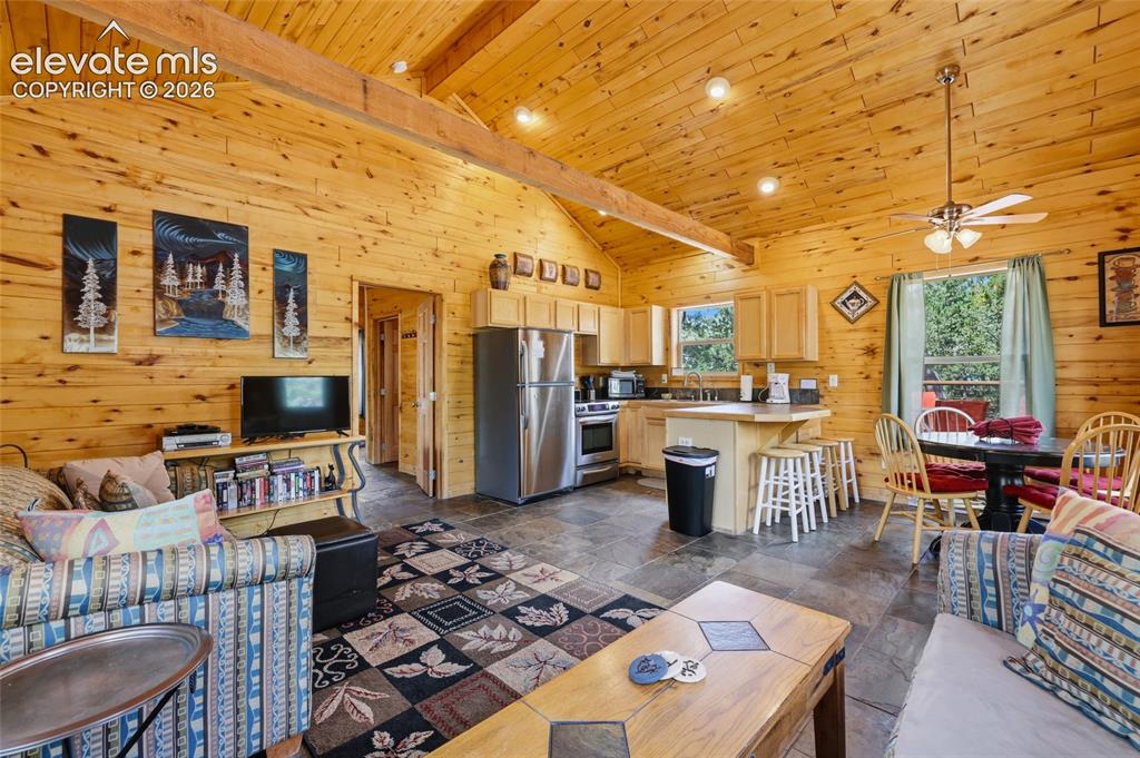 Image 14 of 28: Open-concept living space featuring wood-paneled walls and a vaulted wood c