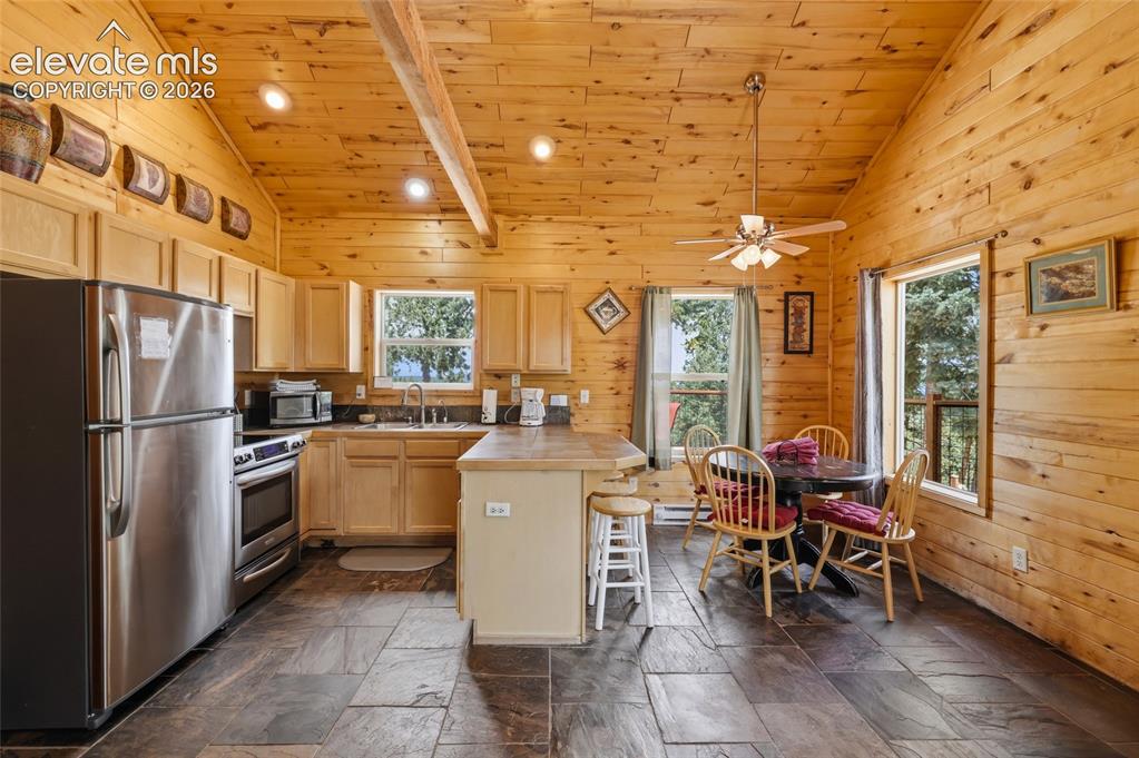 Image 16 of 28: Kitchen featuring natural wood paneling, wood-finish cabinetry, stainless s